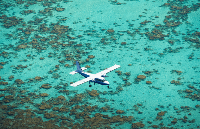 Small plane over clear blue water around our private island resort