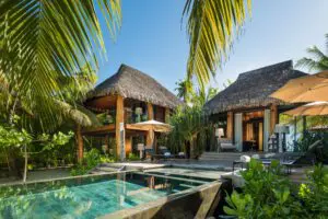 Two thatched-roof buildings around a modern pool in a tropical secluded area at our private island retreat