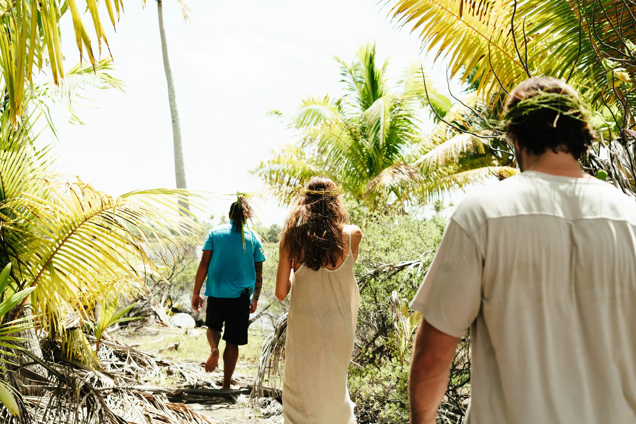 Man leading a couple with grass crowns through a cleared area of palm trees at our Tahiti all inclusive resort