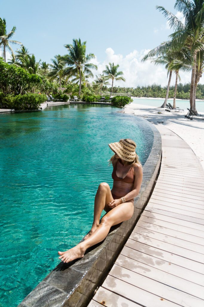 Woman sitting at the edge of a large pool at our private island retreat