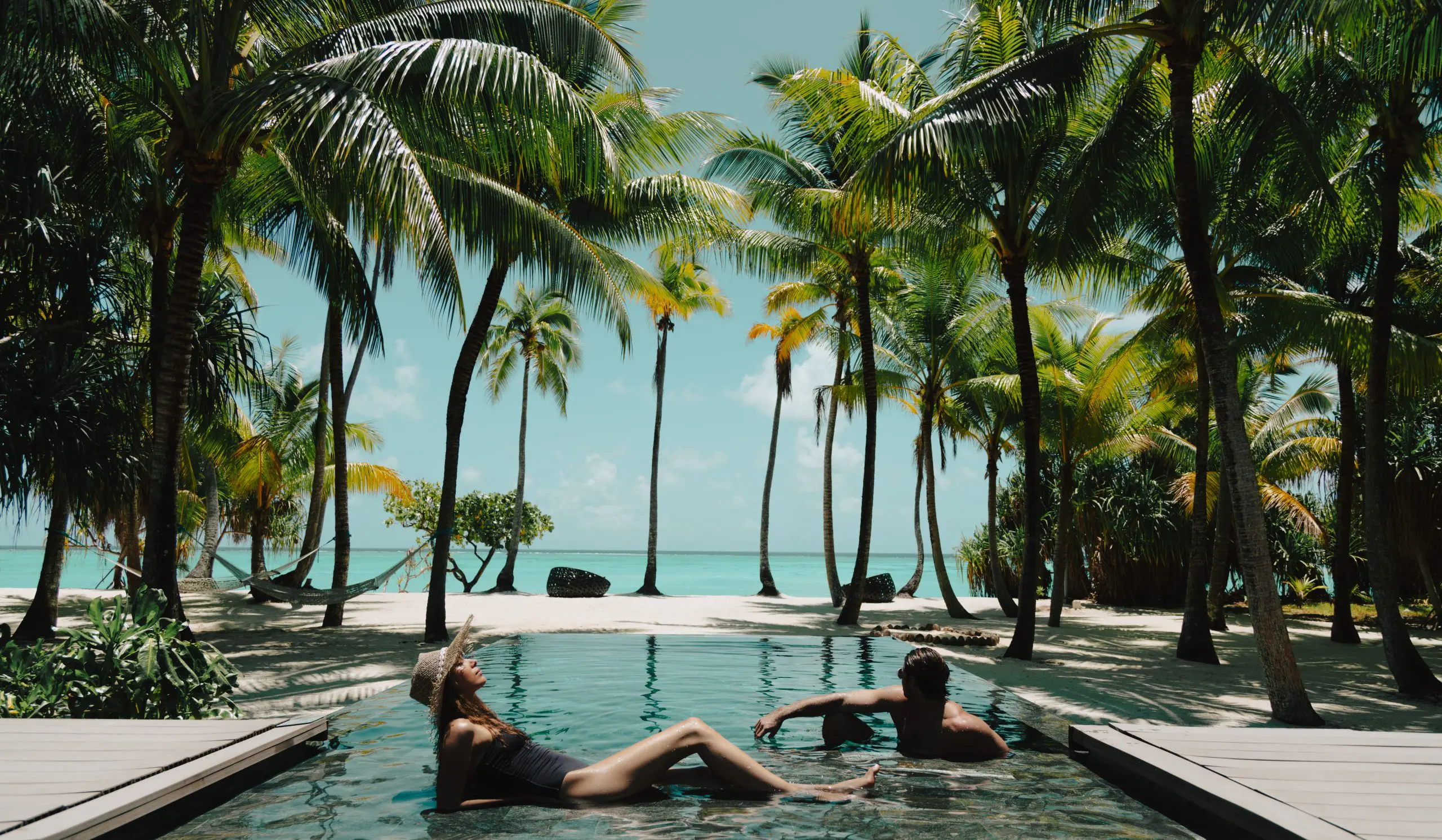 Couple lounging in a pool on the beach at our private island resort