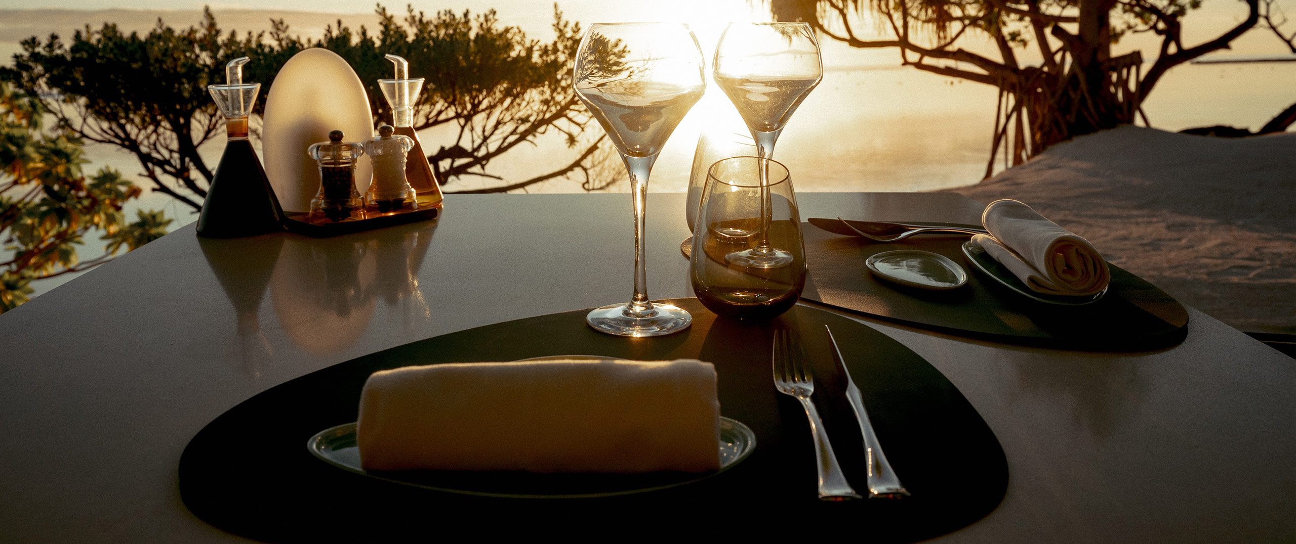 Elegant beachfront dining table set at sunset at The Brando in Tetiaroa, French Polynesia